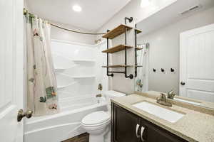 Full bath featuring visible vents, vanity, wood finished floors, shower / bath combination with curtain, and toilet