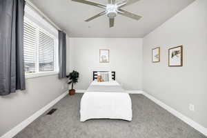 Carpeted bedroom with visible vents, baseboards, and ceiling fan
