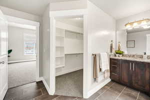 Bathroom featuring baseboards, a spacious closet, tile patterned flooring, and vanity