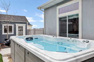 View of pool with a hot tub, fence, and an outbuilding