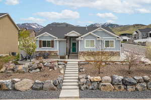 View of front of house featuring board and batten siding, central AC, a mountain view, a patio, and stone siding