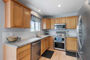 Kitchen featuring appliances with stainless steel finishes, tasteful backsplash, a sink, light wood-style floors, and recessed lighting