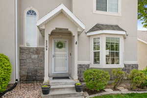 View of exterior entry with stucco siding and stone siding