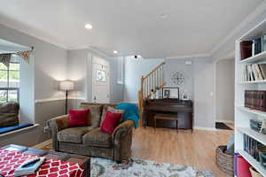 Living room with baseboards, ornamental molding, wood finished floors, and stairway