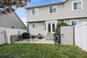 Back of house with a lawn, a fenced backyard, entry steps, and stucco siding