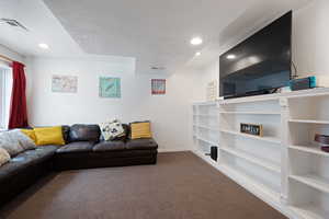 Carpeted living area with visible vents, recessed lighting, a textured ceiling, and baseboards