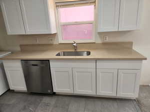 Kitchen with dishwasher, a sink, and white cabinetry