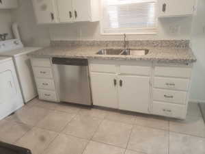 Kitchen featuring light tile patterned flooring, a sink, separate washer and dryer, dishwasher, and white cabinets