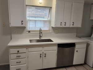 Kitchen with dishwasher, a sink, white cabinetry, and washer / dryer