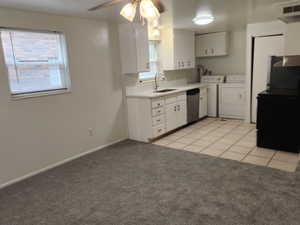 Kitchen featuring visible vents, a sink, separate washer and dryer, stainless steel dishwasher, and light colored carpet