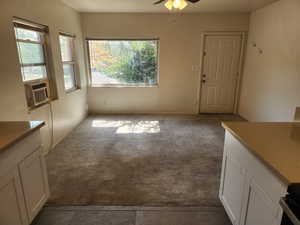 Unfurnished dining area with cooling unit, a ceiling fan, dark tile patterned floors, and dark carpet