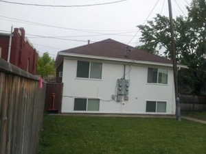 Back of property with stucco siding, fence, and a lawn