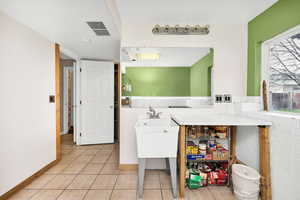 Laundry area featuring light tile patterned flooring and visible vents