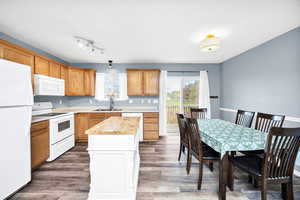 Kitchen featuring a sink, wood finished floors, a kitchen island, and white appliances
