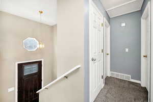 Carpeted hallway with visible vents and baseboards