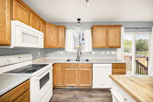 Kitchen with white appliances, a healthy amount of sunlight, a sink, and dark wood-type flooring