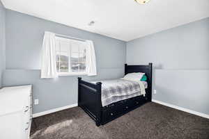 Bedroom featuring baseboards, dark carpet, and visible vents