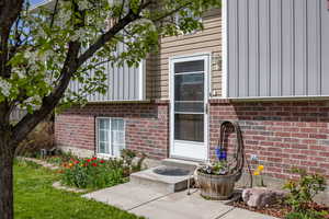 Entrance to property with aluminum board and batten siding and brick siding
