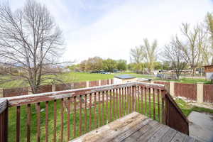 Deck with a fenced backyard, an outdoor structure, a yard, and a shed