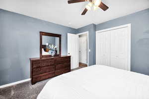 Carpeted bedroom featuring a ceiling fan, baseboards, and a closet