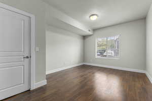 Empty room with baseboards, dark wood finished floors, and visible vents