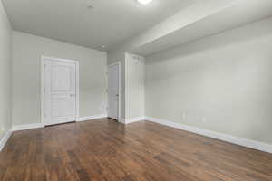 Spare room with dark wood-type flooring and baseboards
