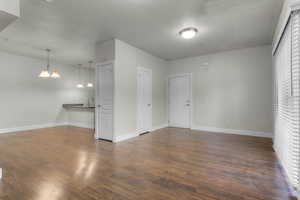 Interior space with dark wood-type flooring, a sink, baseboards, and a chandelier