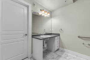 Bathroom with baseboards, a textured ceiling, marble finish floor, and vanity