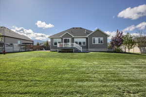 Rear view of house featuring a lawn, a fenced backyard, and a shingled roof