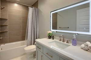 Downstairs Master Bathroom with vanity, tile patterned flooring, toilet, and shower / tub combo with curtain