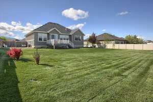 Back of property featuring stucco siding, fence, and a yard