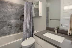 Full bathroom with vanity, shower / tub combo with curtain, and toilet