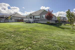 Rear view of property with a yard, fence, and stairs