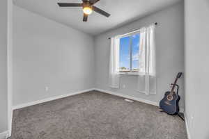 Carpeted empty room with ceiling fan, visible vents, and baseboards