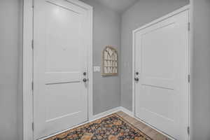 Doorway featuring baseboards and wood finished floors