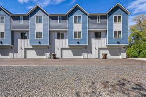 Multi unit property featuring a garage, board and batten siding, and aphalt driveway