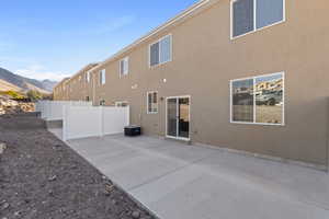 Back of property with fence, a patio, stucco siding, and a mountain view