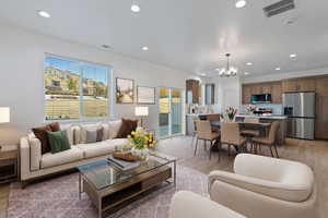 Living room with recessed lighting, a notable chandelier, visible vents, and light wood-type flooring