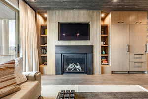 Living area with a fireplace, built in shelves, and wood finished floors