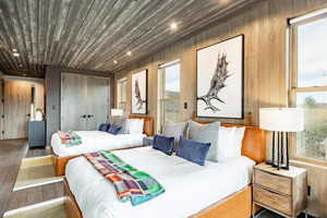 Bedroom featuring wooden walls, recessed lighting, multiple windows, and wood finished floors