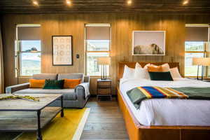 Bedroom with wood-type flooring, recessed lighting, wood walls, and multiple windows