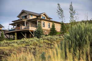 Rear view of property with a deck, metal roof, and stone siding