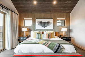 Bedroom with wooden walls, baseboards, wood finished floors, lofted ceiling, and wood ceiling