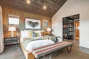 Bedroom featuring wooden walls, high vaulted ceiling, baseboards, wooden ceiling, and wood finished floors