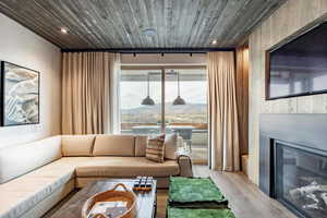Living area featuring recessed lighting, a glass covered fireplace, wooden ceiling, and wood finished floors