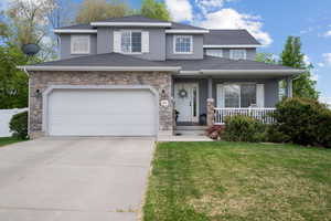 View of front facade featuring stone siding, stucco siding, a porch, a front yard, and concrete driveway