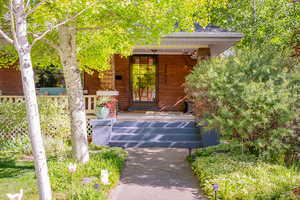 Property entrance featuring covered porch and lush front yard.