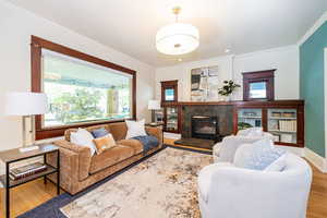 Living room featuring original glass-front built in cabinets, gas-log fireplace and a huge front window.