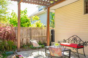 View of second exterior lounge area featuring  a pergola and a fenced backyard