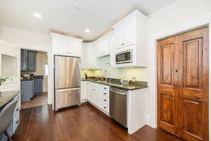 Kitchen with white-painted cherry cabinetry, granite countertops and stainless steel appliances.  Showing entrance to laundry/mudroom.